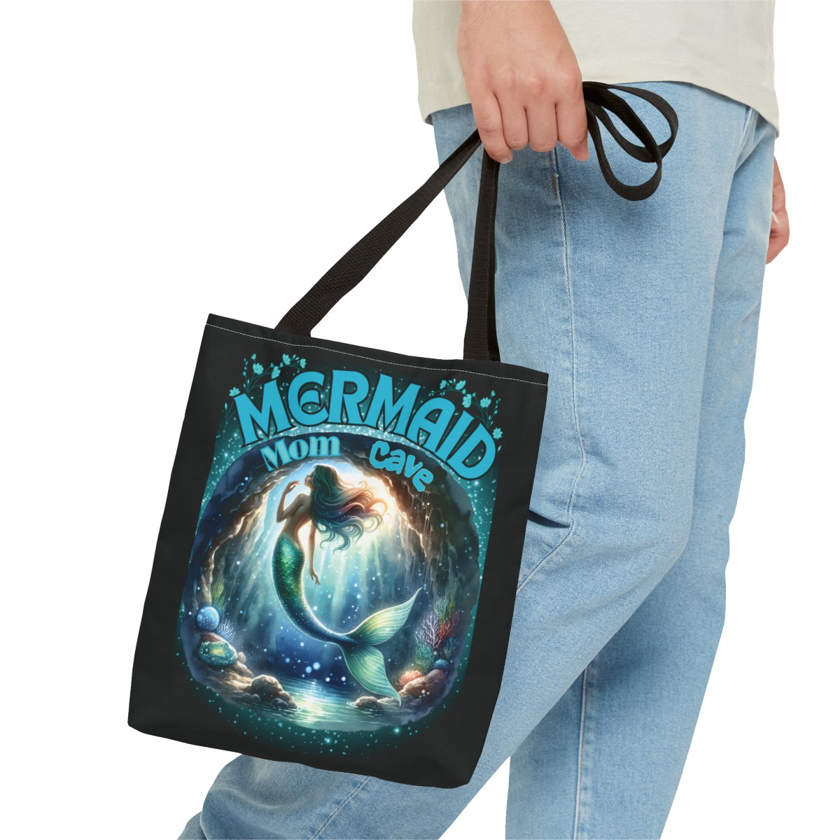 A gorgeous mermaid swims in her mermaid mom cave with her sea shells and plants around her - Mermaid Mom Cave is the text above her cave with blue flowers above the text - black bag - inside too- handles