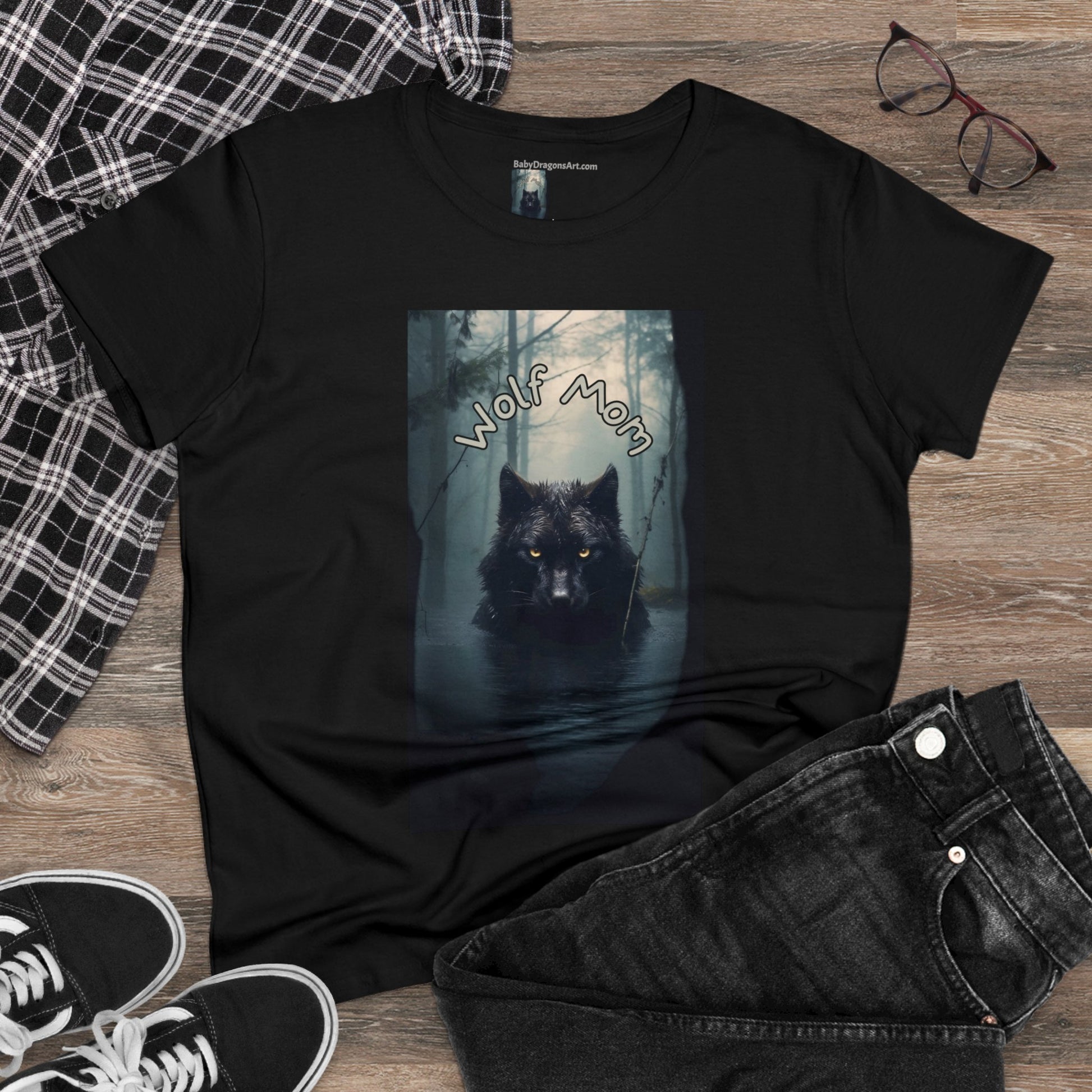 A black wolf with yellow eyes stares directly at you from the center of the tee - dead calm - a misty dark forest is behind the imposing black alpha wolf - the text Wolf Mom sits a few inches above the wolves ears - stunning!